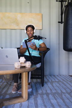 African American adult woman in studio wearing phones holding tablet with weights speaking into mic