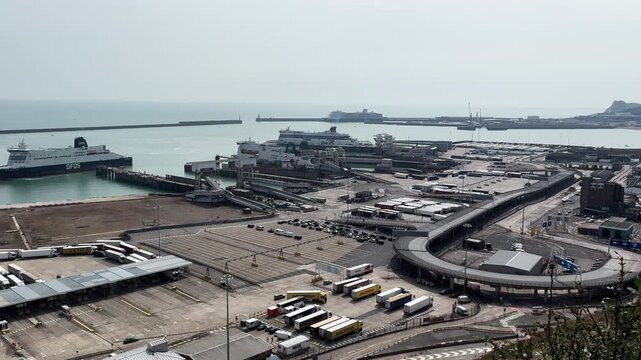 High angle wide view of busy Port of Dover with passenger ferries, cargo trucks, and logistical infrastructure on English coast.