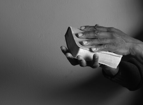 praying to god with hands showing his religious faith with God Caribbean man praying with background with people stock photo stock image