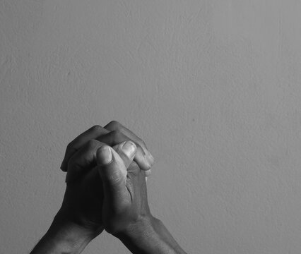 praying to god with hands showing his religious faith with God Caribbean man praying with background with people stock photo stock image