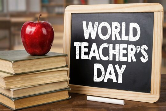 World teachers day concept with a stack of old books, a red apple, and a chalkboard