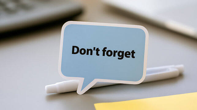 A blue speech bubble note with text dont forget placed on office desk with pen, memory reminder concept for work task and project plan
