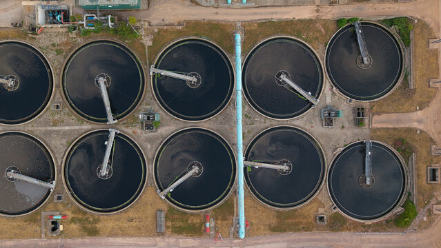 Aerial view of the wastewater treatment plant featuring large circular sedimentation tanks with rotating mechanical arms and industrial infrastructure in Wanlip, England, United Kingdom.