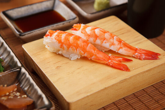 Shrimp nigiri sushi on a wooden serving board
