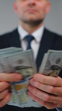 Formally dressed man is counting US Dollar bills, close-up.