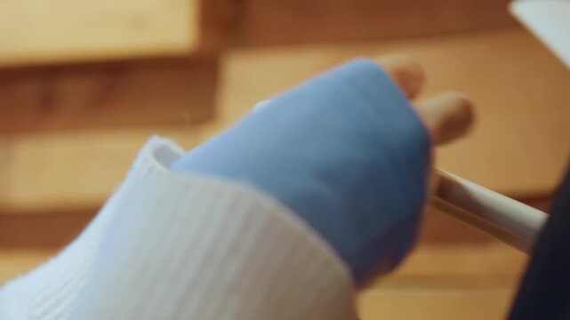 Close up of young girl hands wearing blue fingerless gloves as girl carefully ties and unties string on white fabric demonstrating crafting technique. soft lighting highlights texture