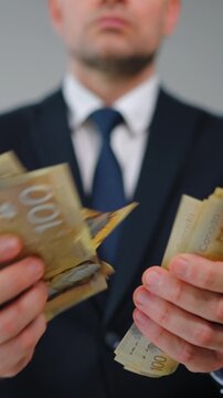 Formally dressed man is counting Canadian Dollar bills, close-up.
