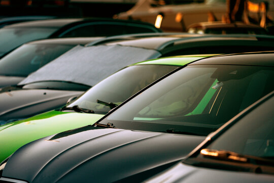 Cars parked outdoors in warm golden hour light with reflections on windshields. Concept of urban traffic, daily commuting, and automotive design.