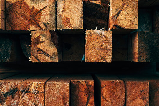 Close-up of stacked rough sawn timber beams showing detailed growth rings, natural wood grain and weathered surfaces. Rustic lumber, forestry, carpentry and construction material concept.