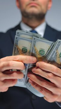 Formally dressed man is counting US Dollar bills, close-up.