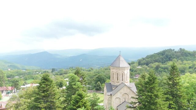 Aerial view flying around the dome of the historic nikortsminda cathedral, a georgian orthodox church in the racha region, showcasing its unique stone architecture and surrounding landscape