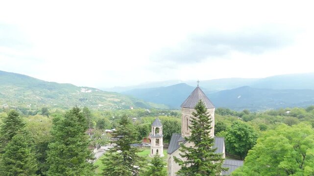 Aerial view flying around the dome of the historic nikortsminda cathedral, a georgian orthodox church in the racha region, showcasing its unique stone architecture and surrounding landscape
