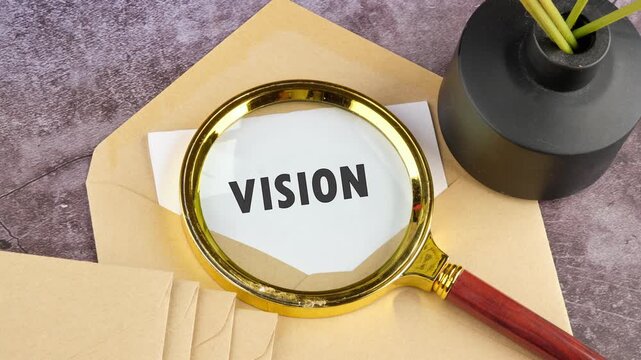 A magnifying glass focuses on the word vision on a white paper over a brown envelope