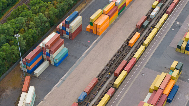 Aerial view of Maritime Hams Hall Rail Terminal featuring colorful shipping containers stacked in rows and loaded onto a freight train in Birmingham, England, United Kingdom.