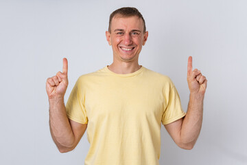 Fototapeta premium Smiling man pointing both index fingers upwards, indicating ample copy space above for advertising messages, promotions, or important information on a clear background