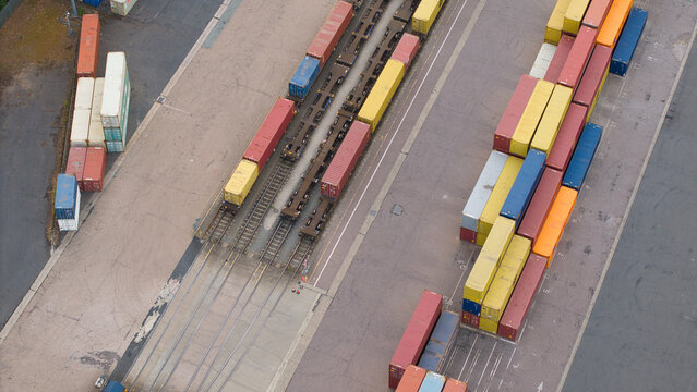 Aerial view of Maritime Hams Hall Rail Terminal featuring rows of colorful shipping containers stacked on the ground and loaded onto freight trains in Birmingham, England, United Kingdom.