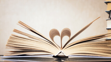 Fototapeta premium Open book on dark wooden surface, minimalist still life.