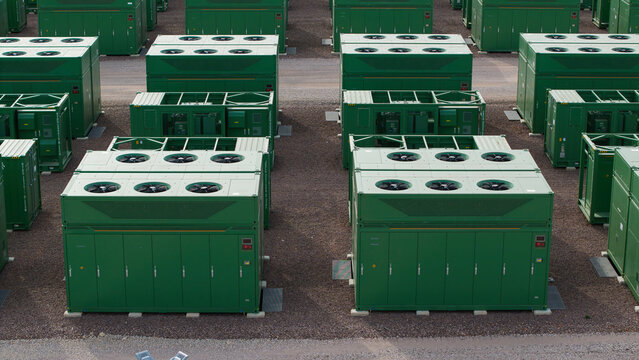 Aerial view of a large-scale Battery Energy Storage System facility with rows of green industrial battery containers and cooling fans in Birmingham, England, United Kingdom.