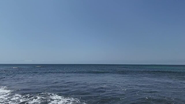 Ocean waves rolling onto sandy beach on sunny day