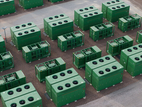 Aerial view of Battery Energy Storage Systems units arranged in rows on a gravel site, showcasing grid resilience infrastructure, Birmingham, England, United Kingdom.