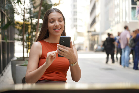 Young happy Brazilian business woman using mobile phone in Sao Paulo downtown street, Brazil
