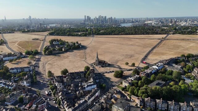 Climate change drought near Canary Wharf London aerial drone view of Blackheath park turned brown and beige UK heatwave impact The dry parched landscape contrasts with the surrounding residential