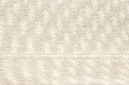 Light cream woven fabric texture with horizontal seam close up