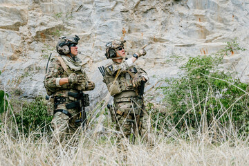 Naklejka premium Two focused outdoor soldiers in jungle gear on duty watchfully scan rugged landscape with alert expressions and determined gaze