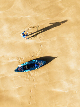 Top Down view fo woman with kayak over Beach from a drone,  North Devon and Cornwall Coastpath Border from a drone, Welcombe Mouth Beach, Devon, Cornwall, England