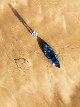 Top Down view fo woman with kayak over Beach from a drone,  North Devon and Cornwall Coastpath Border from a drone, Welcombe Mouth Beach, Devon, Cornwall, England