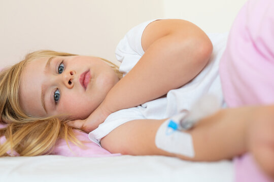Sick Young Girl Receiving Intravenous Treatment in Bed
