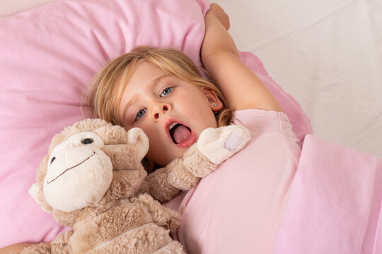 Happy Young Girl Waking Up and Stretching in Bed