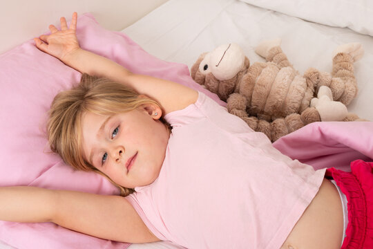 Happy Young Girl Waking Up and Stretching in Bed