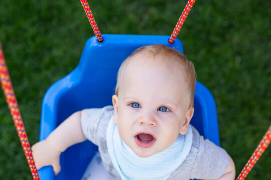 Curious Baby Sitting in a Blue Outdoor Swing