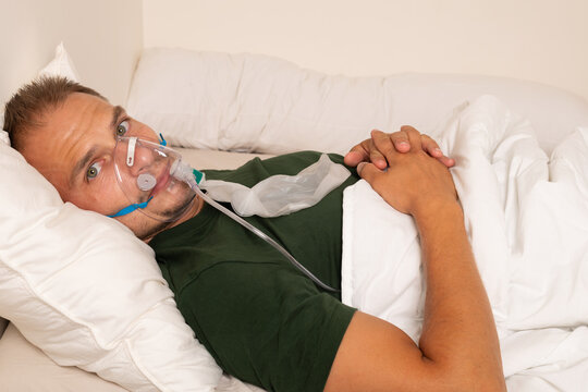 Sick Man Receiving Oxygen Therapy Through Face Mask While Lying in Bed