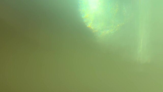 Abstract green light leaks moving across a futuristic background with shimmering bokeh effects, creating a dreamy and ethereal visual for artistic projects