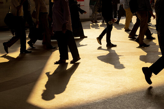 Dhaka, Bangladesh - 03 December 2020: View of commuters walking across the concrete floor at Kamlapur Railway Station during the golden hour with long shadows cast by the late afternoon sun.