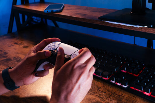 Person gaming with controller at illuminated desk