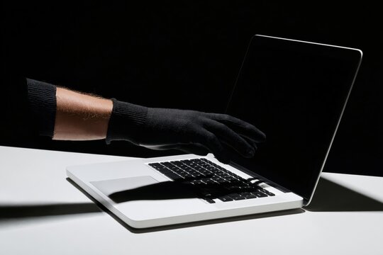Hacker using a laptop in a dark room representing cybercrime and digital security