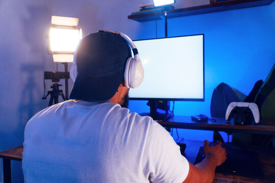 Adult male gamer playing video game at home studio