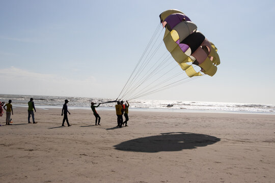 Cox's Bazar, Chittagong Division, Bangladesh - 18 August 2023: View of people preparing for parasailing on the sandy beach with the ocean in the background.