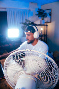 Male streamer gaming online at computer in room