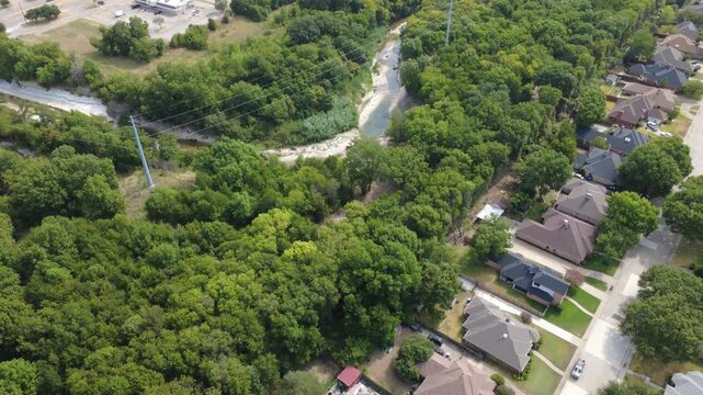 Limestone creek bends carve past Mesa Verde neighborhood within southern DFW suburbs. Blue swimming pools, utility pylons, mature shade trees show distinctive residential buffers, DeSoto, Texas