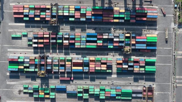 Rows of stacked cargo containers waiting for transport at a busy port facility in Indonesia