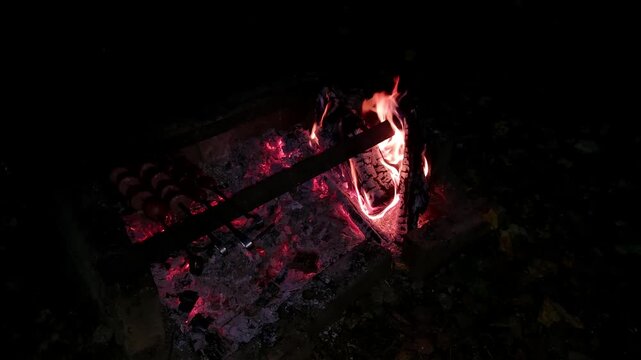 Campfire glowing in the dark with burning logs and embers  
