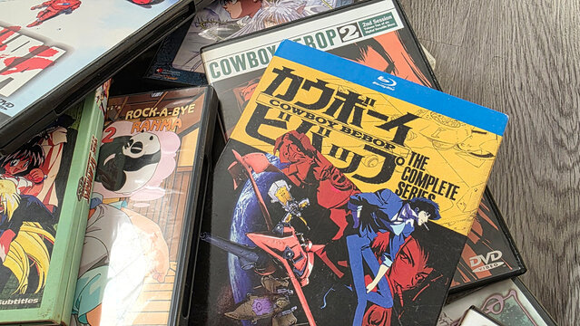 closeup of random collection of 1990s anime dvd cases including Cowboy Bebop, Ranma 1/2 and Akira on a wood surface, August 25, 2026 Schaumburg, IL