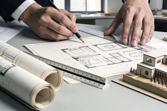 Close-up of hands sketching architectural floor plan with pencil and ruler