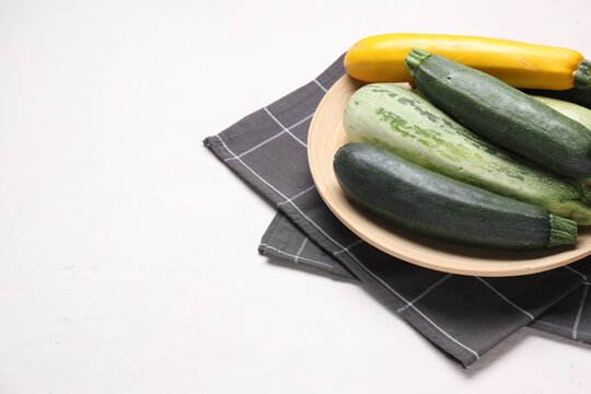 Different fresh raw zucchinis on light table, closeup. Space for text