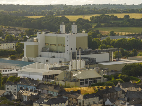 Aerial view of a large industrial factory complex with tall smokestacks situated among residential buildings and green fields in Mallow, County Cork, Ireland.