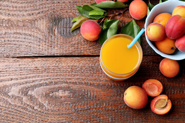 Apricot juice in glass, fresh fruits and leaves on wooden table, flat lay. Space for text © New Africa